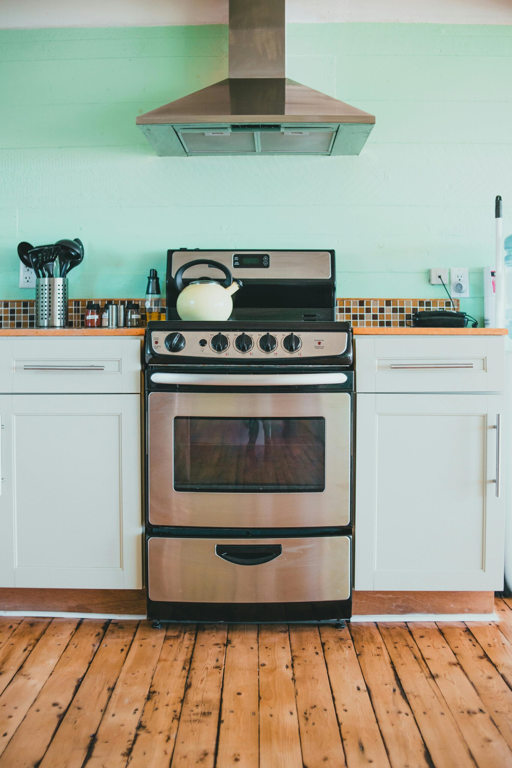 Bright modern kitchen featuring a stainless steel oven and mint-colored walls.